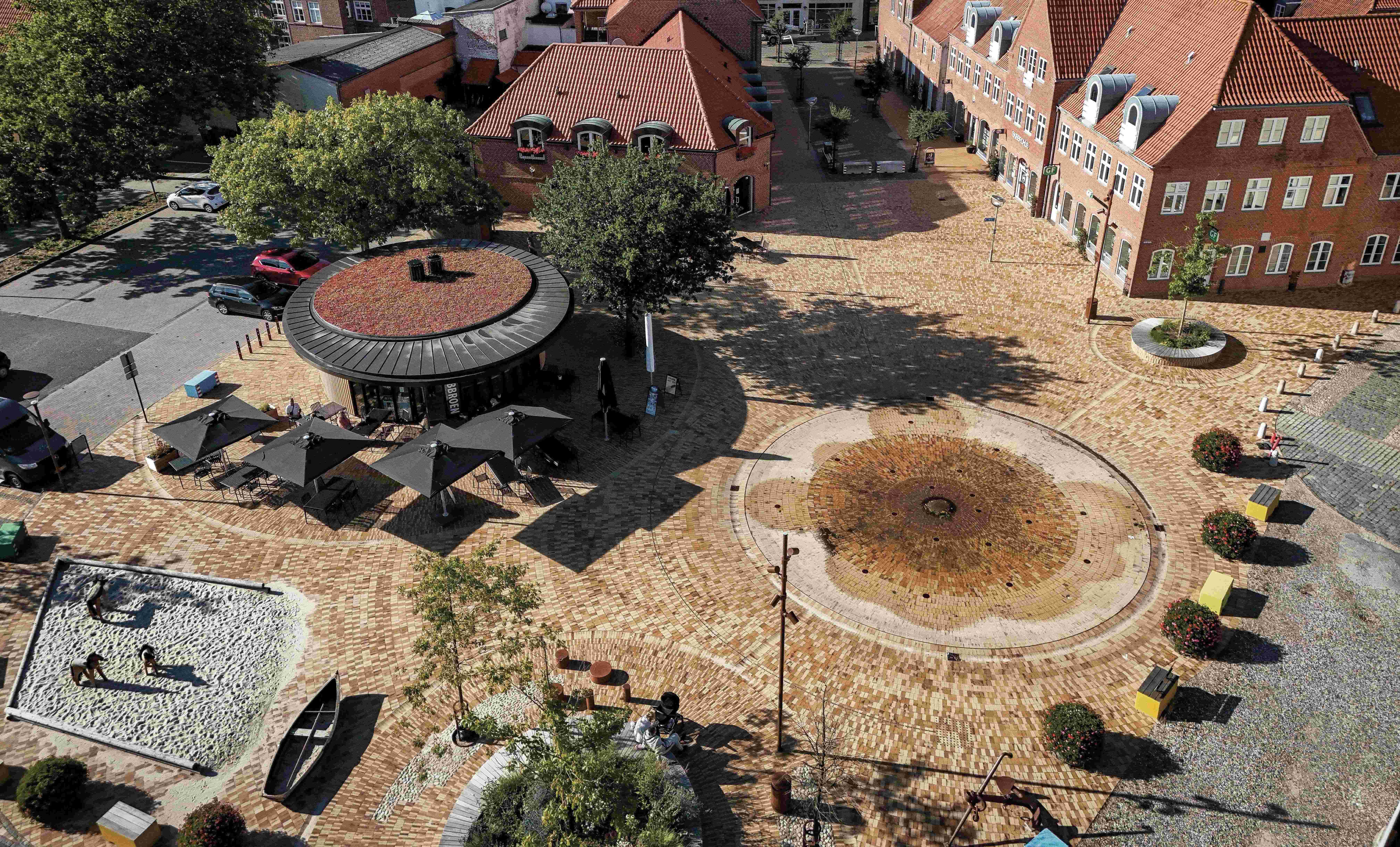 Mit Pflasterklinker gestalteter Platz in historischem Kontext mit Brunnen